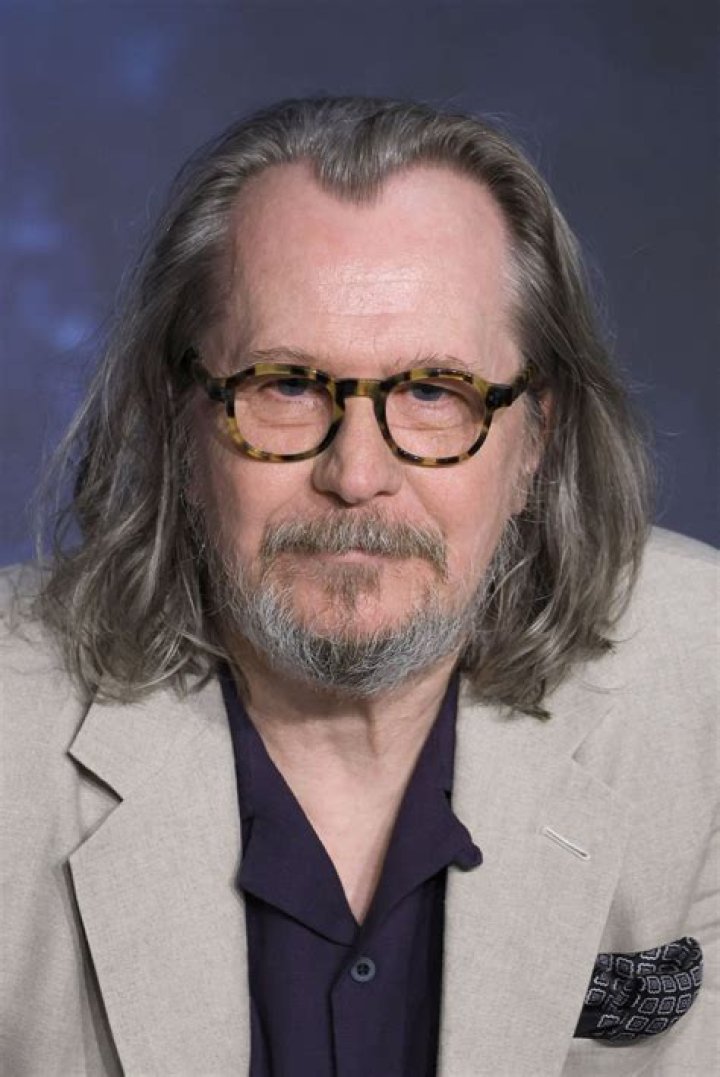 Gary Leonardo Oldman in a noir t-shirt playing the piano.